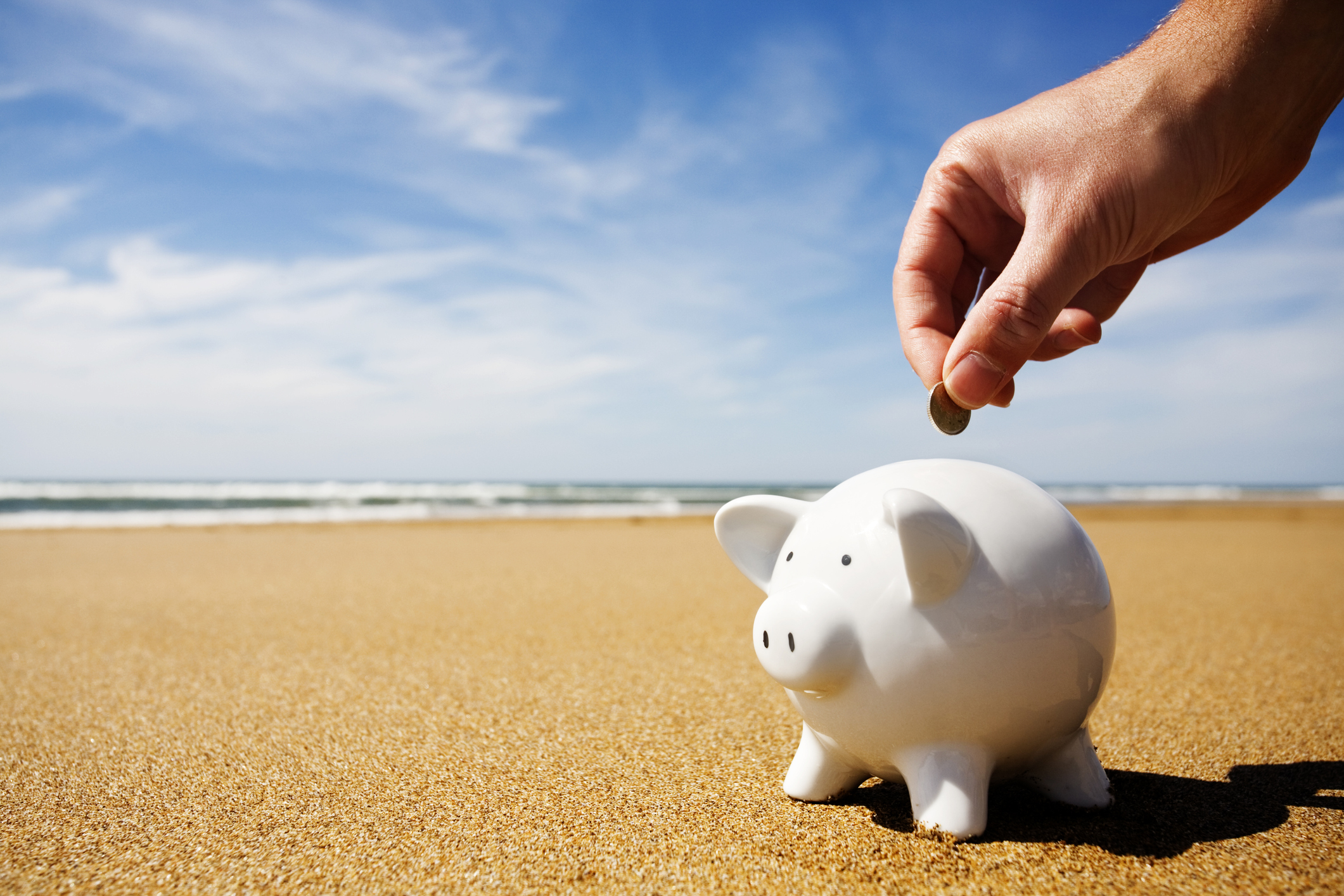 Piggy bank being filled at the seaside -- deals and offers